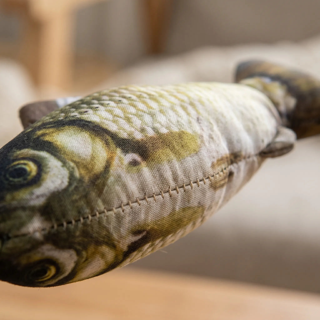 Gros plan détaillé sur l'impression réaliste des écailles et les coutures de la peluche en forme de poisson pour chat.