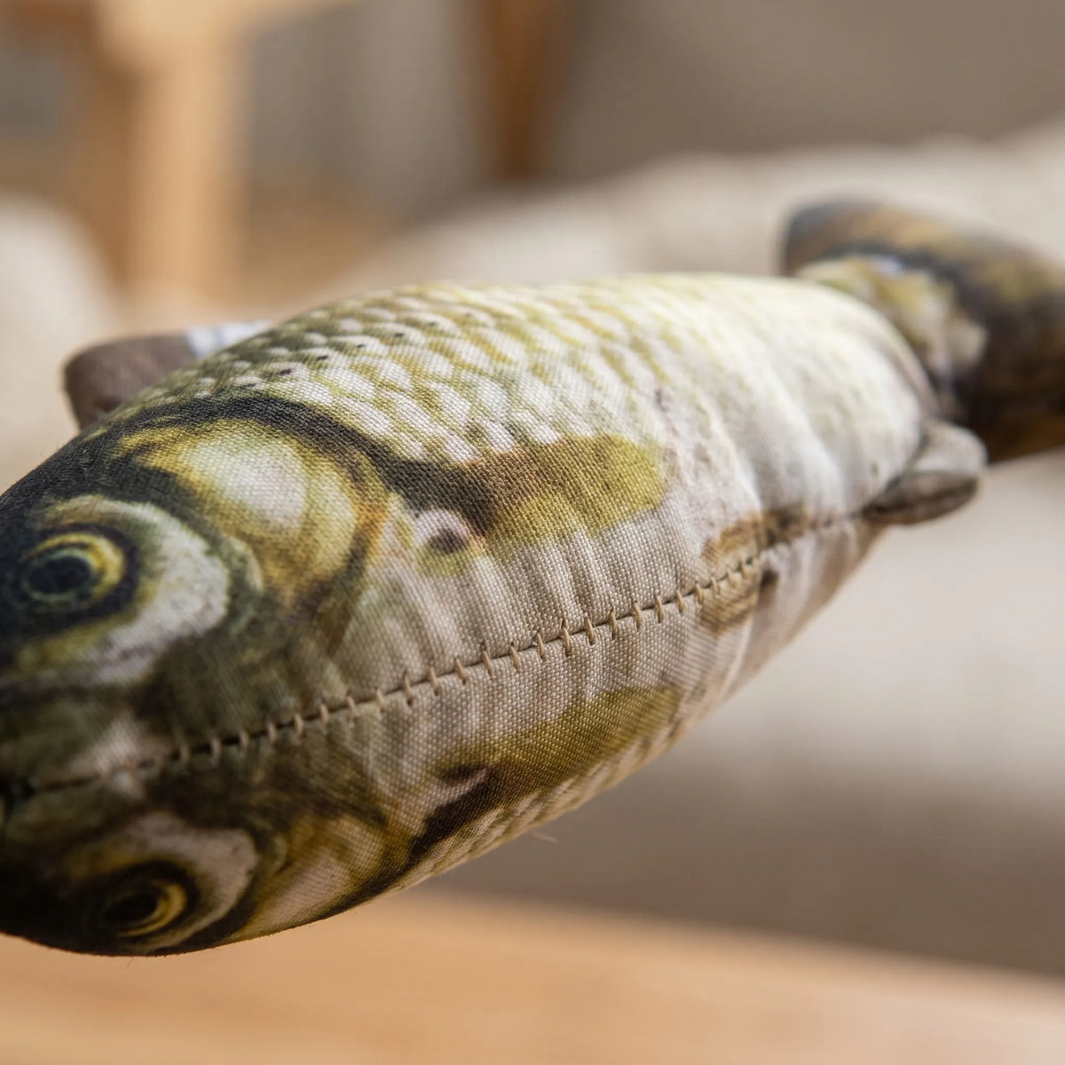 Gros plan détaillé sur l'impression réaliste des écailles et les coutures de la peluche en forme de poisson pour chat.
