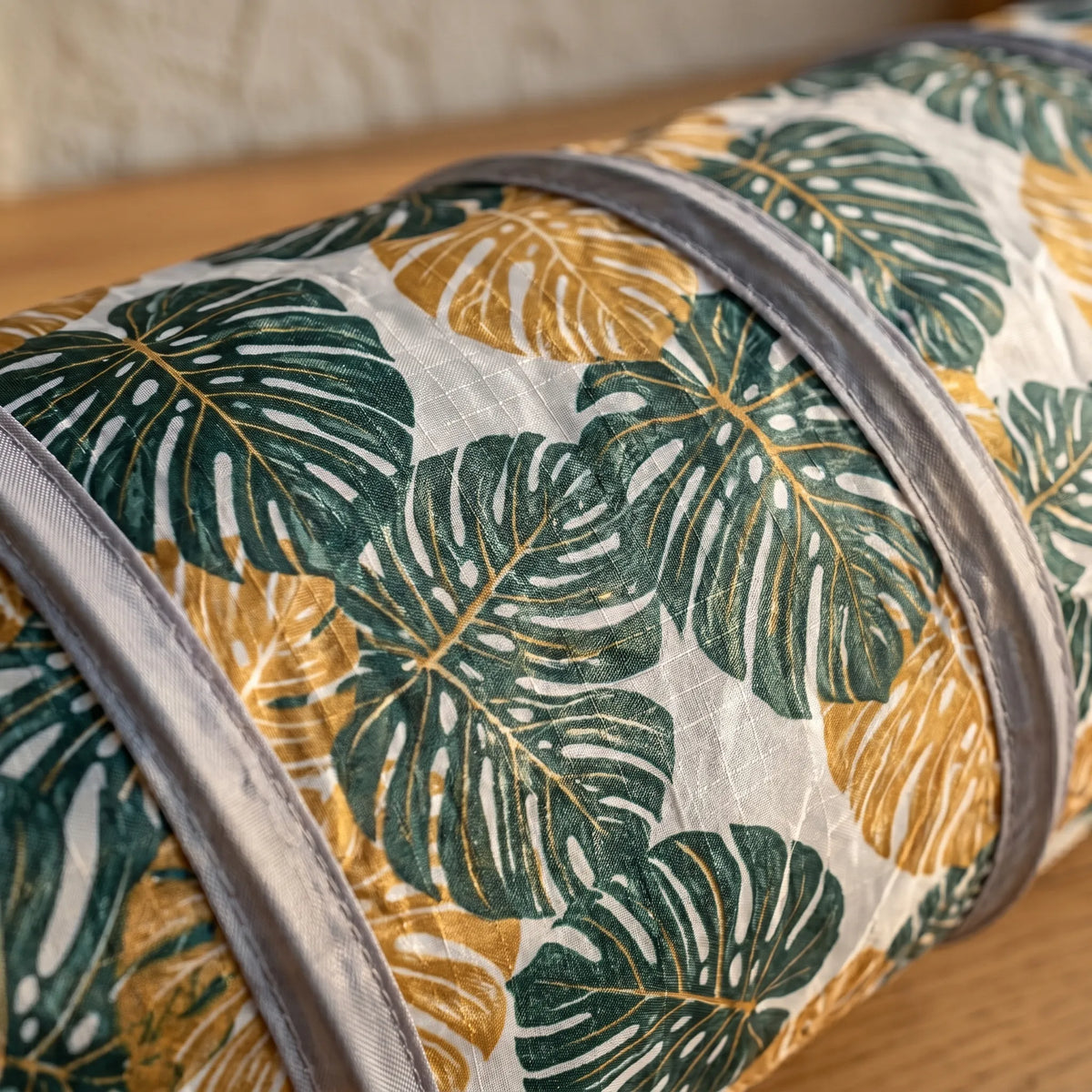 Gros plan sur le tissu et le motif de feuilles de monstera d'un tunnel de jeu pour animaux de compagnie.
